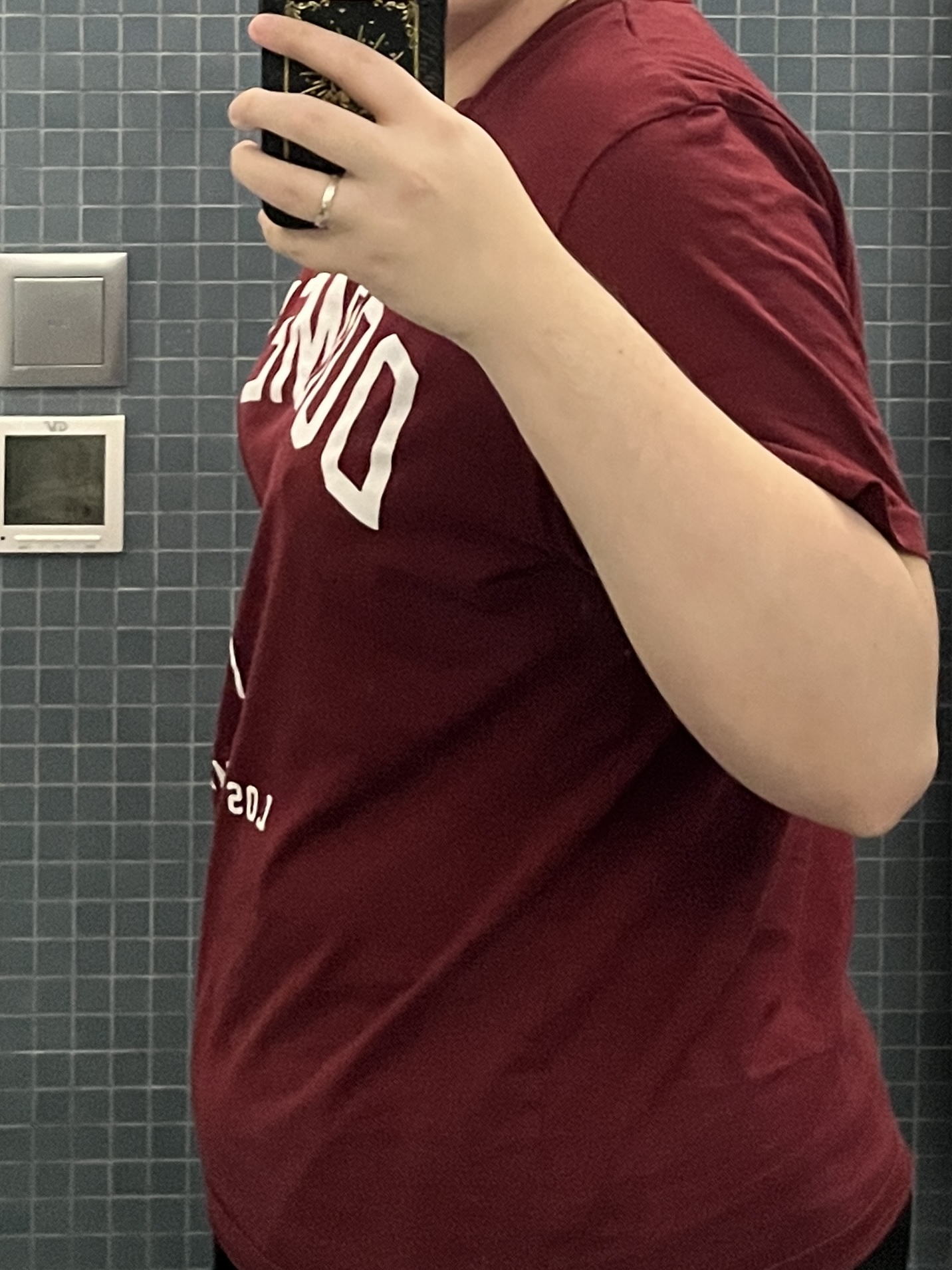 Trans man wearing a red shirt facing sideways